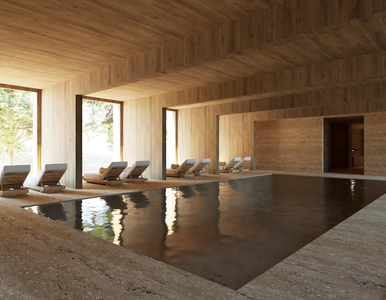 The indoor stone-clad pool at the AMAIA hotel spa, lit by a soft skylight overhead.